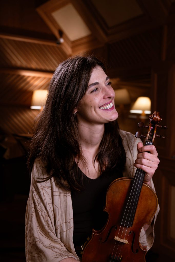 Mathilde Fillat, branca de cabelo liso, segura um violino sorridente.